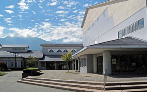 2階建てのコンクリート造りの飯島町文化館の建物の入り口と植木の写真