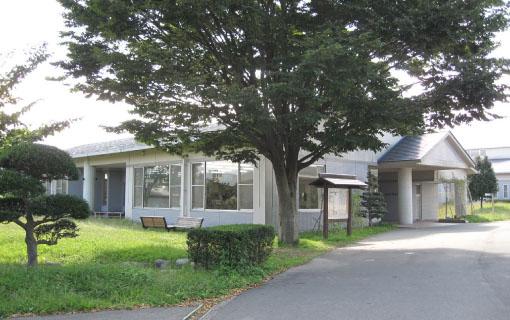 一本の大きな木の横に建っている飯島町図書館の建物の写真