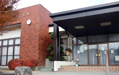 レンガの外壁とガラス張りで黒い屋根がついた入り口の田切公民館の写真