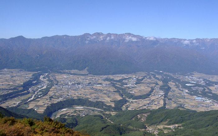 高台から撮影した、遠くに連なる山脈と田畑や民家の写真