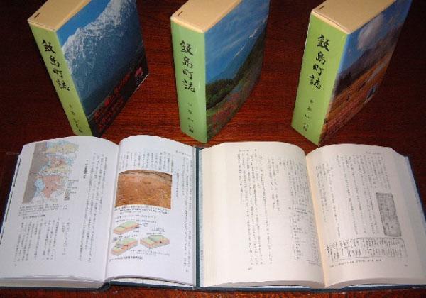 机の上に3冊の飯島町誌が立てて置かれ、2冊が中身が開いた状態で置かれてある写真