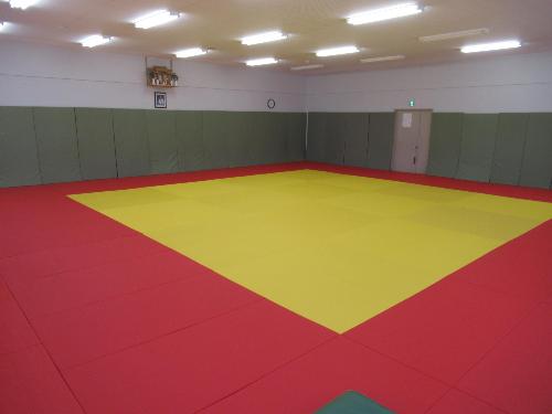 柔道場。黄色と赤色の畳が敷かれている。