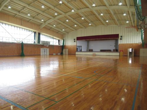 体育館アリーナ。照明はLED化され床はフローリング。バスケットボールコートが2面とれる。正面にはステージ。