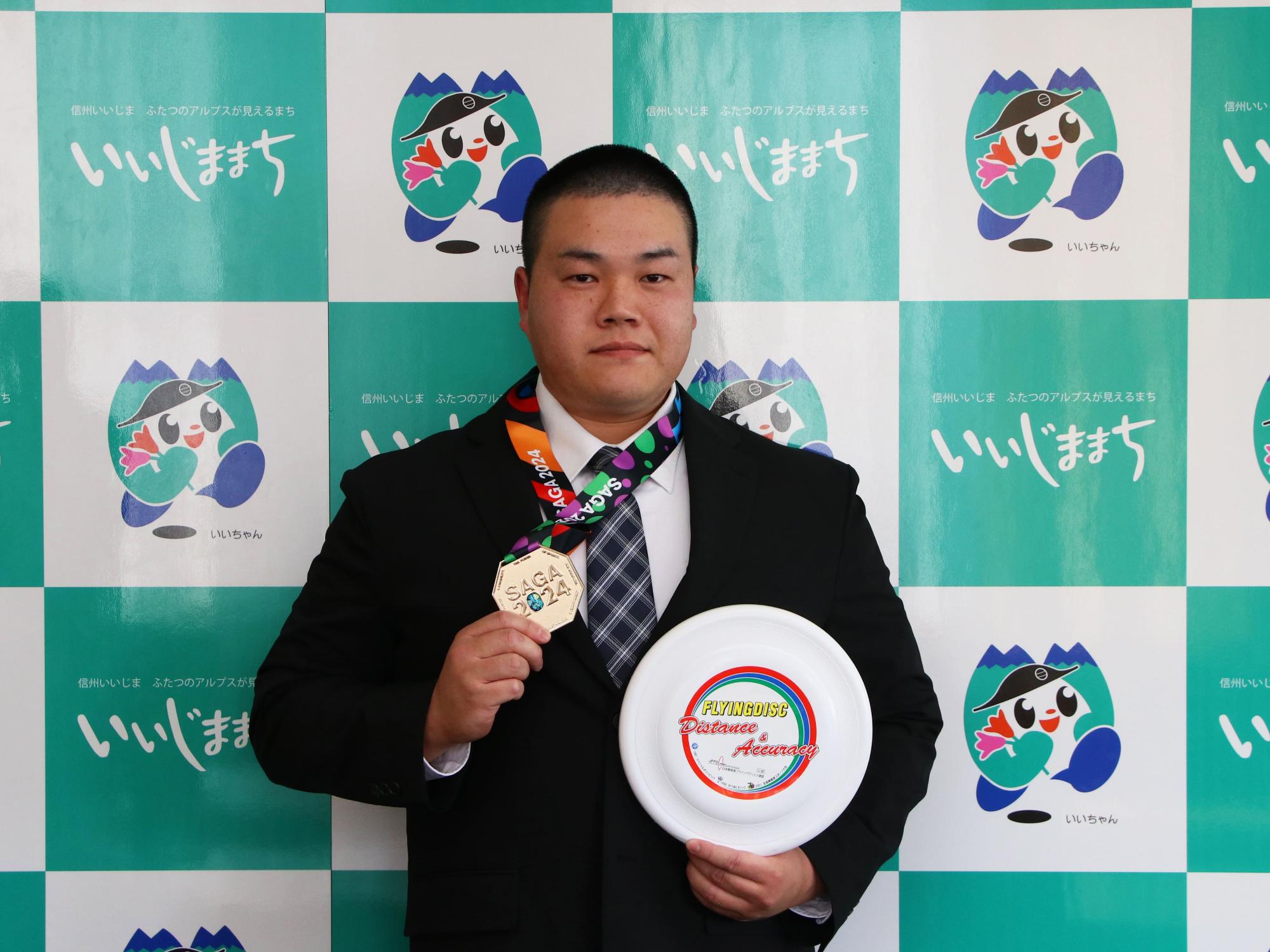 金メダルとフライングディスクを持つ斉藤耕さん