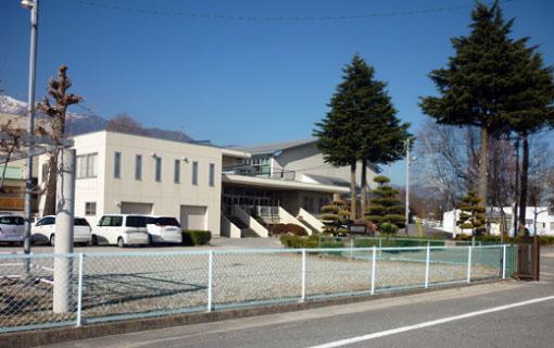 七久保小学校の校舎と校内の植木、学校と道路を隔てているフェンスの写真