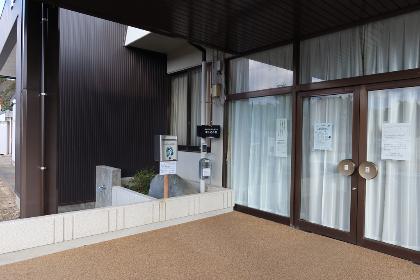田切公民館のレンガ造りの外壁と黒い屋根の入り口に設置されたいいちゃんポストの写真