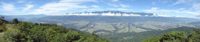 青い空と遠くに見える山々、高台から見下ろした田畑の風景の写真